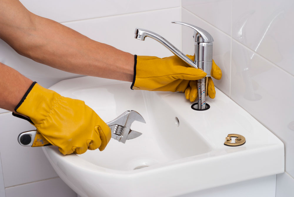 plumber installs a new faucet for a sink