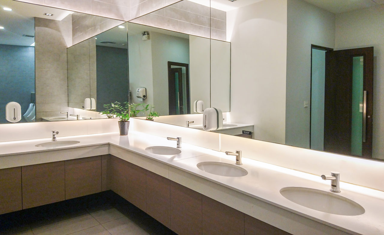 A commercial space/office bathroom showing the vanity area and double-wall mirror
